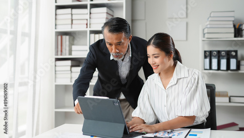 Fotografie Senior manager is showing something on a tablet to a younger female employee in