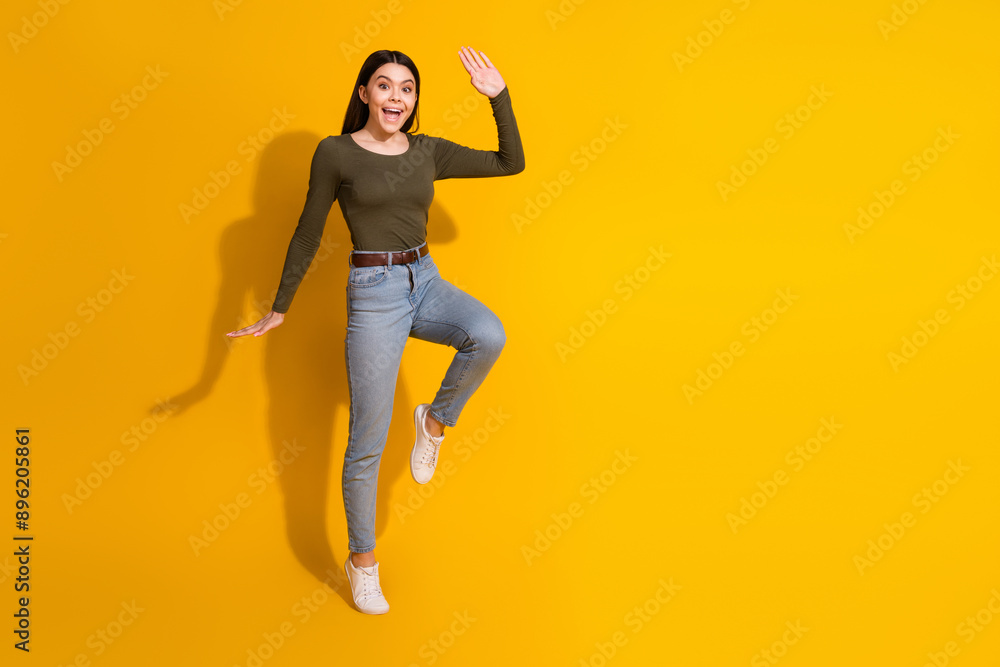 Full size photo of pretty teenager girl step wave hand hello wear trendy khaki outfit isolated on yellow color background Full size photo of pretty teenager girl step wave hand hello wear trendy khaki outfit isolated on yellow color background