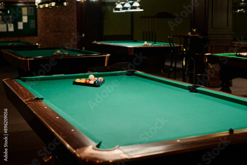 Wallpaper Mural One of several wide wooden tables with rack containing billiards balls on green top standing in front of camera in spacious hall or bar Torontodigital.ca