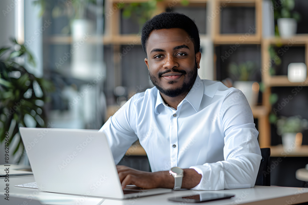 Handsome African American man in his 30s wearing a white shirt in the office, working in the modern office, looking in the camera Handsome African American man in his 30s wearing a white shirt in the office, working in the modern office, looking in the camera