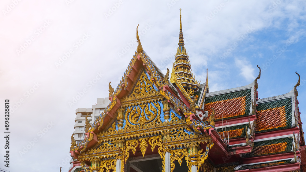 Fototapeta premium Stunning architecture of a traditional Thai temple with intricate details and vibrant colors against a clear blue sky.
