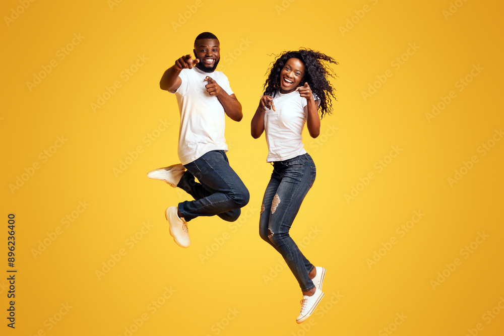 Carefree Black Millennial Man And Woman Are Jumping In The Air, yelllow background Carefree Black Millennial Man And Woman Are Jumping In The Air, yelllow background