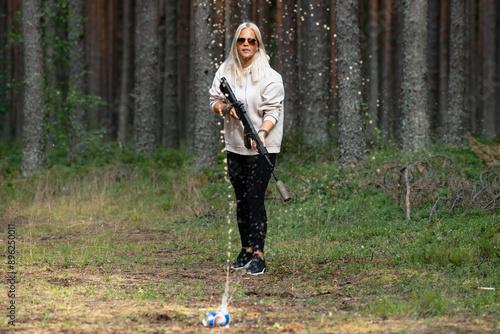 A young girl shoots from a pneumatic weapon at cans in nature on a summer day. photo