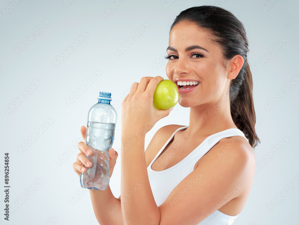 Portrait, apple and model with water in studio for nutrition, diet or lose weight on blue background. Healthy body, bottle and happy woman with fruit for fitness, workout goals or digestion benefits Portrait, apple and model with water in studio for nutrition, diet or lose weight on blue background. Healthy body, bottle and happy woman with fruit for fitness, workout goals or digestion benefits