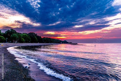 Photography dawn over kew beach toronto with firey red orange and blue sky reflected in the