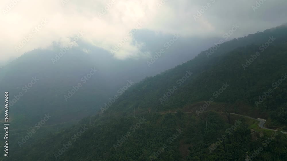 Aerial view of a dangerous winding road along a lush green mountain cliff leading to the Ha Giang Loop in Vietnam Aerial view of a dangerous winding road along a lush green mountain cliff leading to the Ha Giang Loop in Vietnam