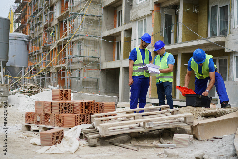 Engineer coworker in protective workwear discussing while working together at construction site Engineer coworker in protective workwear discussing while working together at construction site