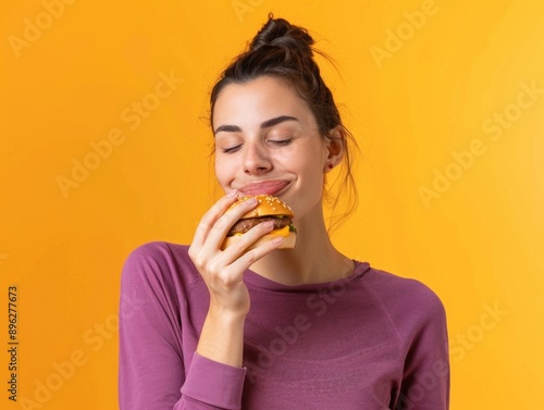 A woman is eating a hamburger and smiling