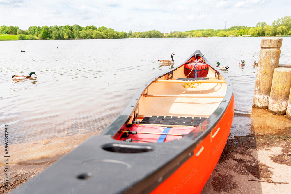 Fototapeta premium Red Canoe Docked at Lake on Sunny Day