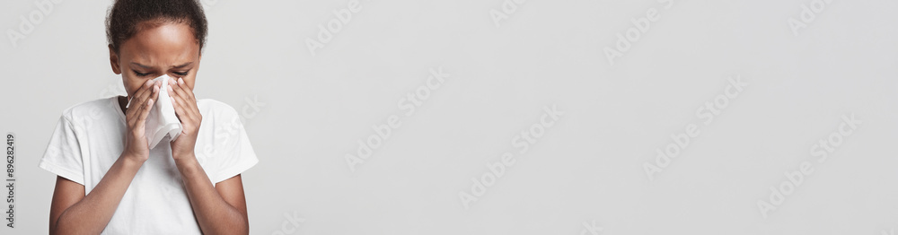 Sickness, illness, virus concept. Little african girl blowing nose over grey studio background Sickness, illness, virus concept. Little african girl blowing nose over grey studio background