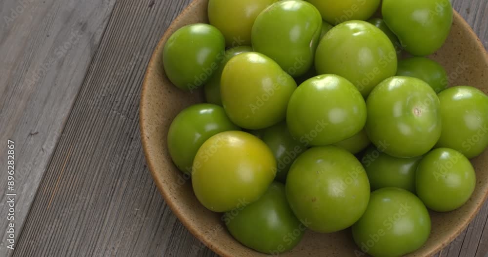 A heap of husked tomatillo in a bowl on rustic wooden table. Copy space, table spin. A heap of husked tomatillo in a bowl on rustic wooden table. Copy space, table spin.