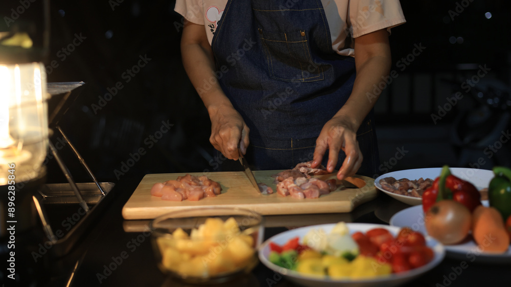 A woman prepares ingredients and prepares BBQ. Grilling for the party in the night. A woman is getting ingredients ready and grilling BBQ for a party at night. A woman prepares ingredients and prepares BBQ. Grilling for the party in the night. A woman is getting ingredients ready and grilling BBQ for a party at night.