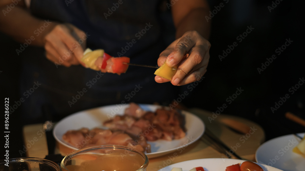 A woman prepares ingredients and prepares BBQ. Grilling for the party in the night. A woman is getting ingredients ready and grilling BBQ for a party at night. A woman prepares ingredients and prepares BBQ. Grilling for the party in the night. A woman is getting ingredients ready and grilling BBQ for a party at night.