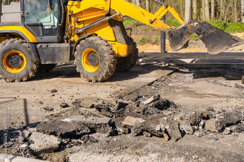 Obraz premium Yellow Excavator Removing Asphalt During Road Construction