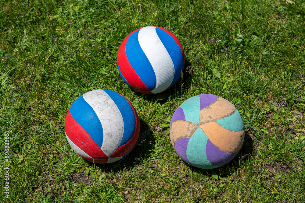 Three volleyballs on green grass. Sports equipment.