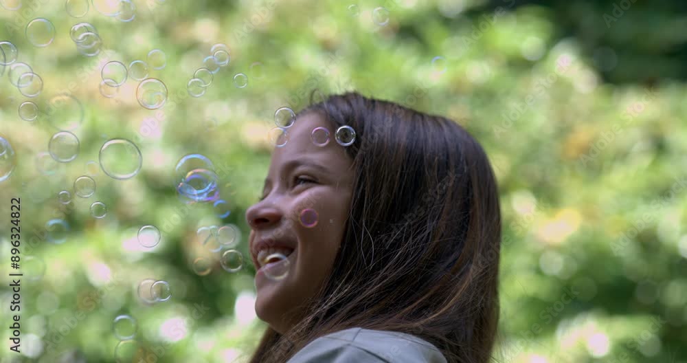 Young girl laughing joyfully while surrounded by floating bubbles in slow-motion at 800 fps, enjoying a playful and magical moment outdoors on a sunny day Young girl laughing joyfully while surrounded by floating bubbles in slow-motion at 800 fps, enjoying a playful and magical moment outdoors on a sunny day