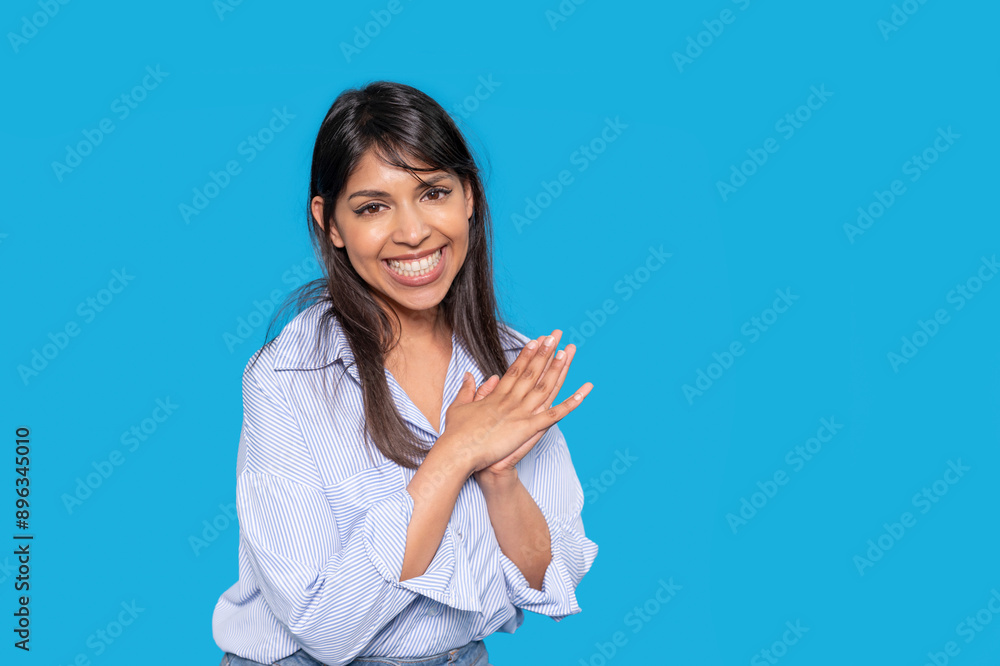 Woman in Blue Striped Shirt Clapping With a Big Smile Against a Blue Background Woman in Blue Striped Shirt Clapping With a Big Smile Against a Blue Background
