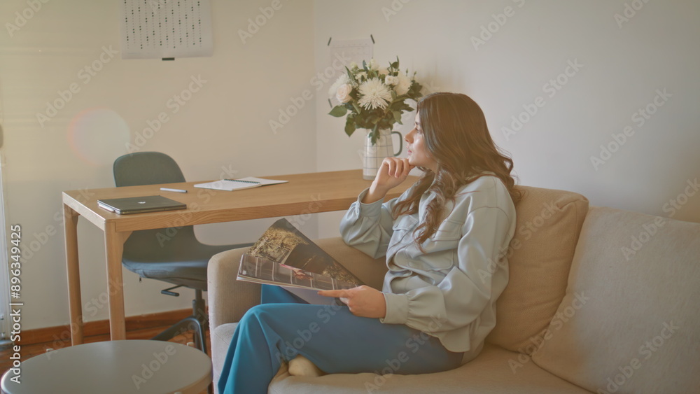 Thoughtful model resting sofa holding magazine at sunlight home. Woman relaxing Thoughtful model resting sofa holding magazine at sunlight home. Woman relaxing
