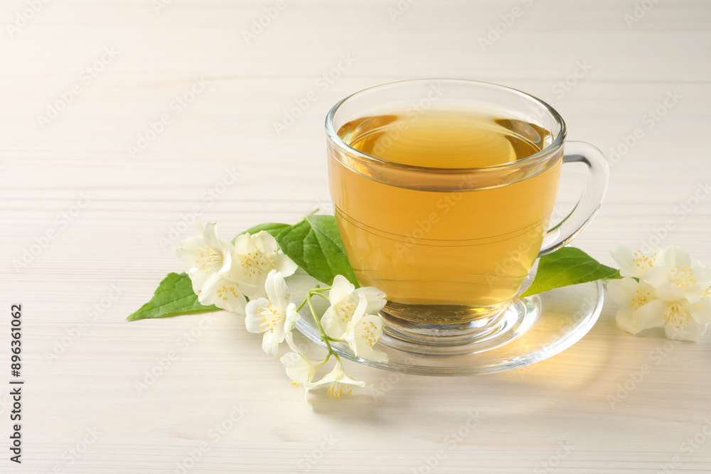 Hot jasmine tea in cup and flowers on white wooden table Hot jasmine tea in cup and flowers on white wooden table