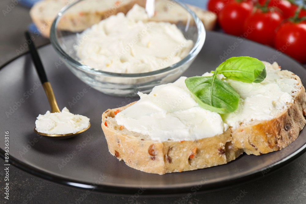 Piece of bread with cream cheese and basil leaves on gray table, closeup Piece of bread with cream cheese and basil leaves on gray table, closeup