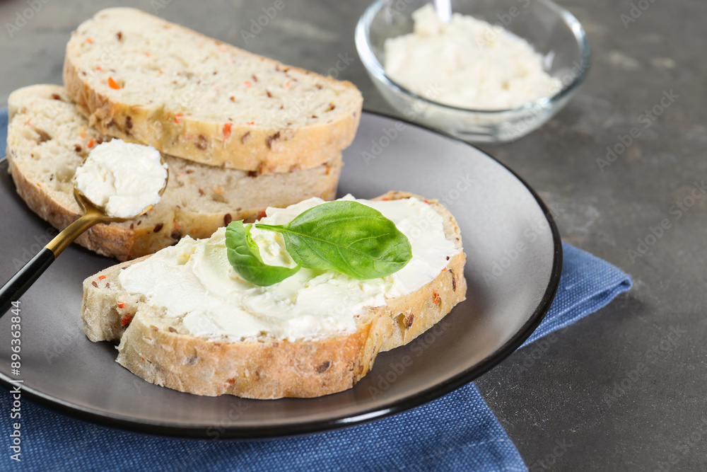 Pieces of bread with cream cheese and basil leaves on gray textured table, closeup Pieces of bread with cream cheese and basil leaves on gray textured table, closeup