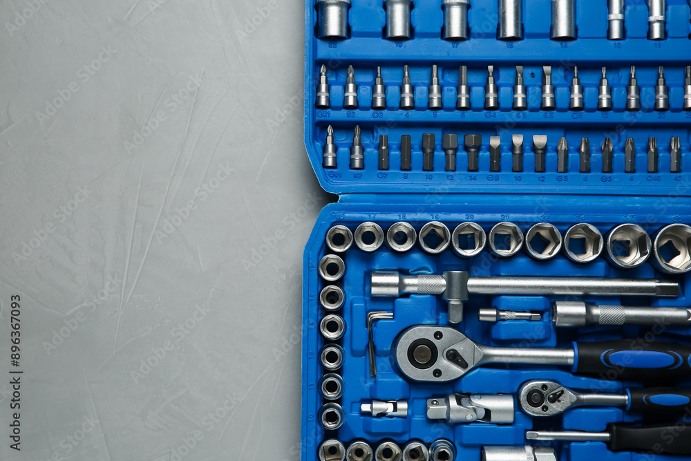 Different auto mechanic's tools in plastic box on grey table, top view. Space for text Different auto mechanic's tools in plastic box on grey table, top view. Space for text