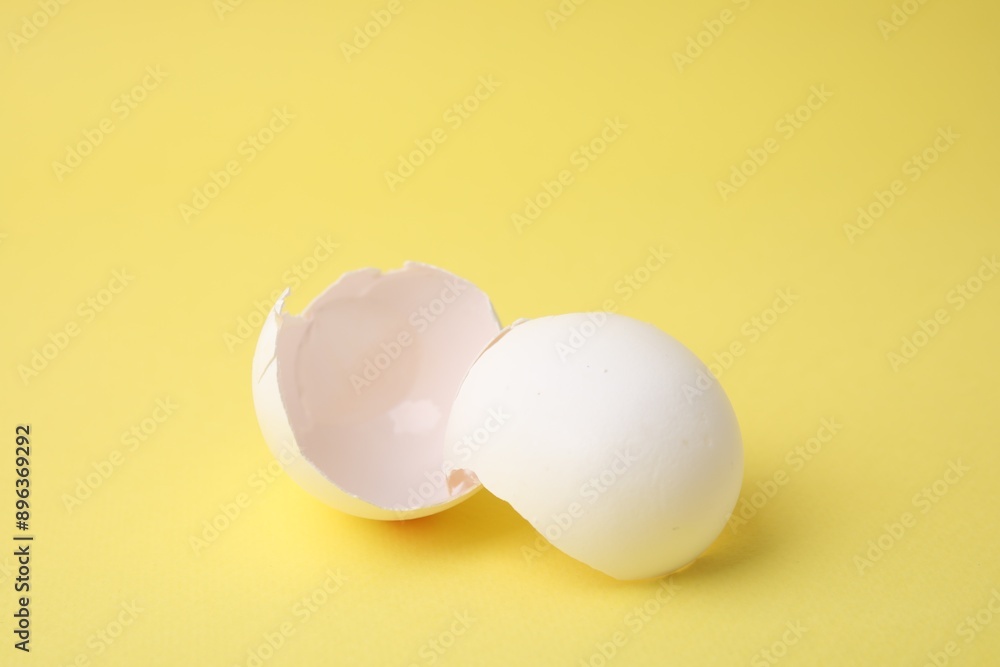 Pieces of broken eggshells on yellow background, closeup Pieces of broken eggshells on yellow background, closeup