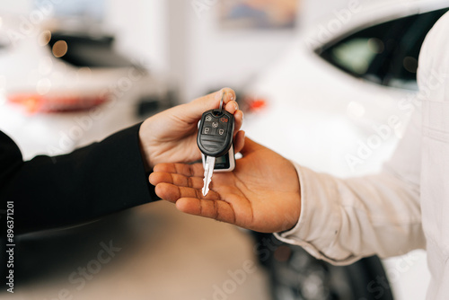 Fotografie Detail cropped shot of unrecognizable black male buyer getting car key and greetings from auto dealer while buying new auto in dealership