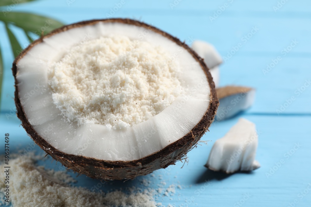Fresh coconut flour in nut on light blue wooden table, closeup Fresh coconut flour in nut on light blue wooden table, closeup