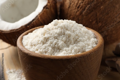 Coconut flour in bowl and fresh fruits on table, closeup