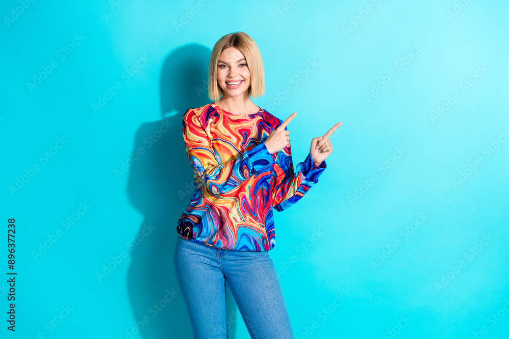 Photo of positive nice girl with bob hairstyle dressed print shirt indicating at offer empty space isolated on blue color background Photo of positive nice girl with bob hairstyle dressed print shirt indicating at offer empty space isolated on blue color background