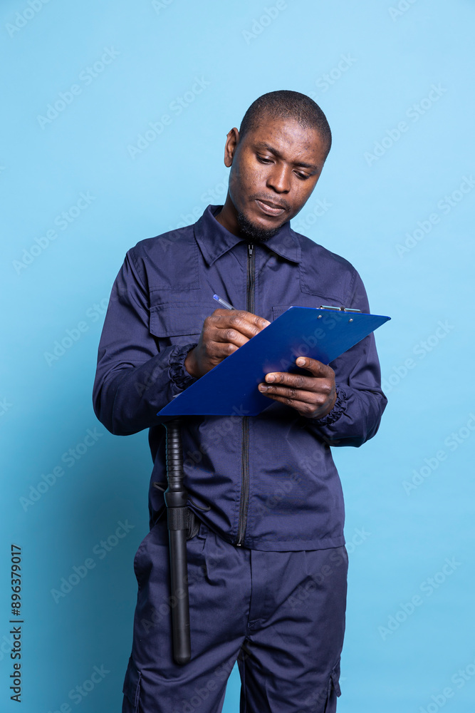 African american security agent takes notes on files to keep evidence of responsibilities while he is on duty. Trained guard works on safeguarding and protecting the premises, clipboard papers. African american security agent takes notes on files to keep evidence of responsibilities while he is on duty. Trained guard works on safeguarding and protecting the premises, clipboard papers.