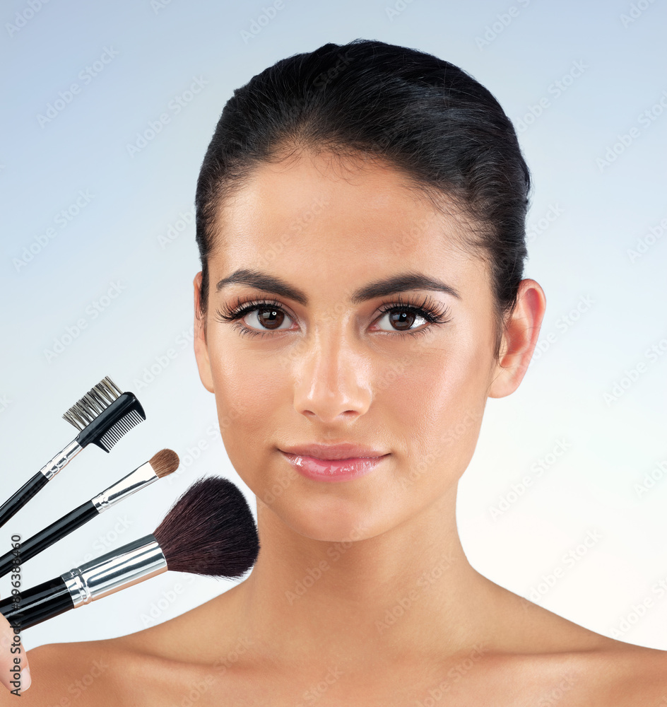 Portrait, woman and makeup with brush in studio for cosmetic application, beauty transformation and salon glow. Female person, facial and product tools for aesthetic makeover on blue background Portrait, woman and makeup with brush in studio for cosmetic application, beauty transformation and salon glow. Female person, facial and product tools for aesthetic makeover on blue background