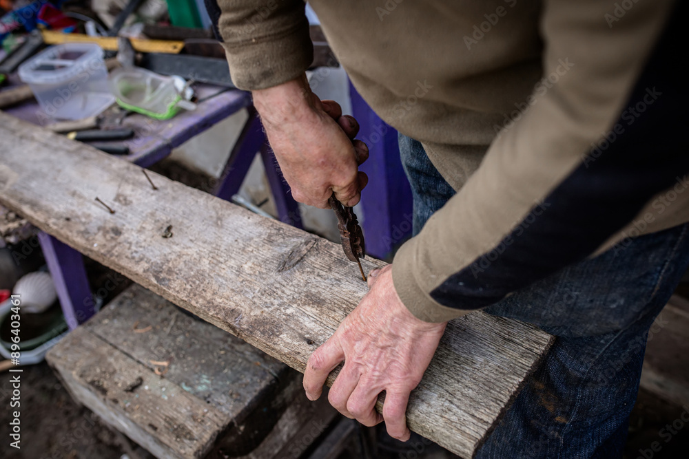 Person Using Pliers to Remove Nails From Old Wood Plank Person Using Pliers to Remove Nails From Old Wood Plank