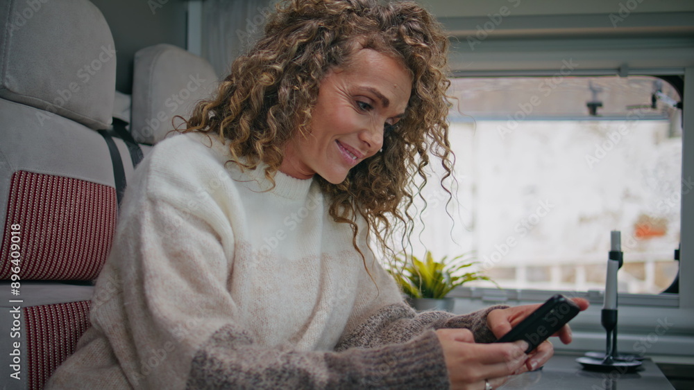Cheerful lady watching social media at cellphone in camper van close up. Cheerful lady watching social media at cellphone in camper van close up.