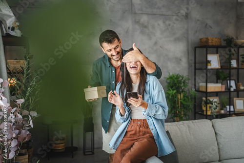 Fotografie Boyfriend hold gift and surprise his girlfriend close eyes and hide