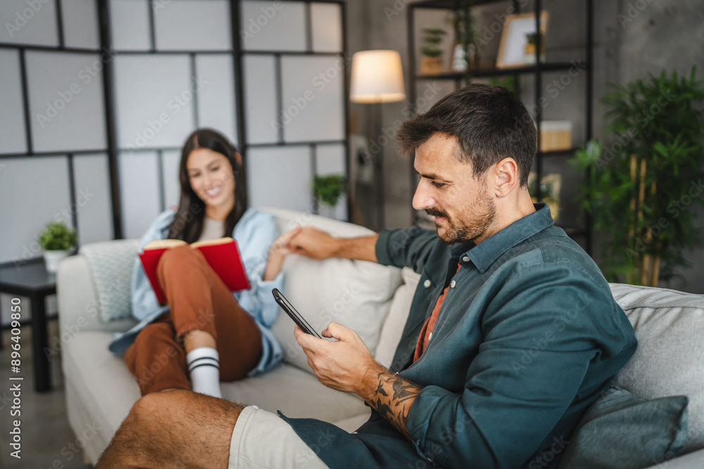 relaxed couple girlfriend read a book and boyfriend use mobile phone relaxed couple girlfriend read a book and boyfriend use mobile phone