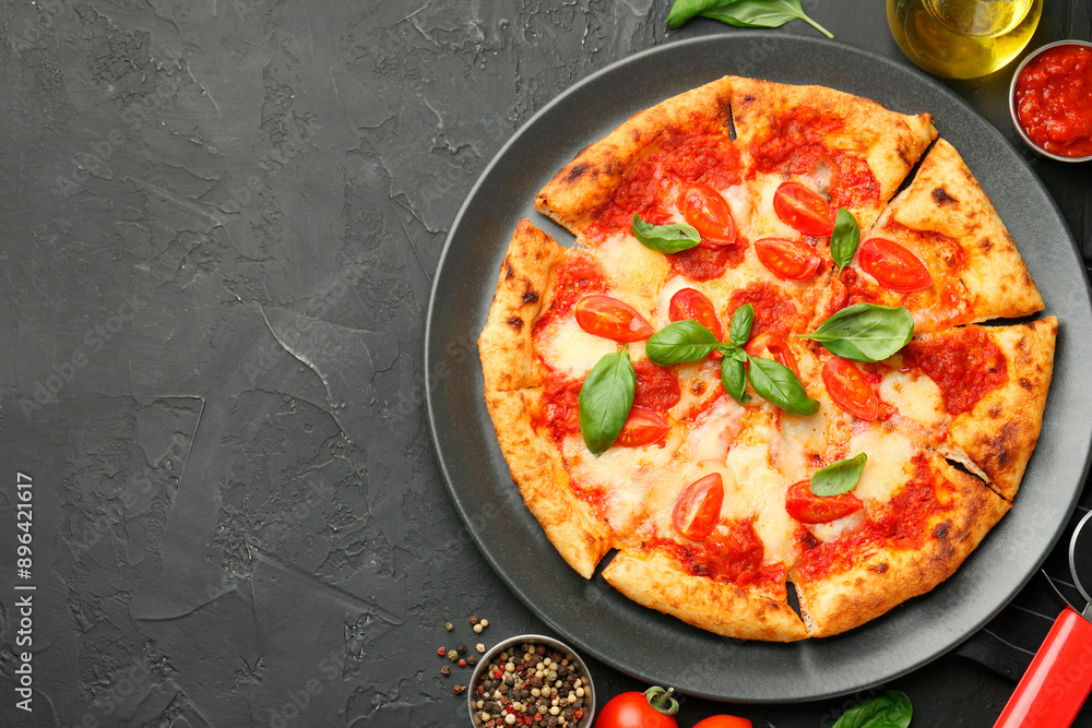 Delicious Margherita pizza and ingredients on black table, top view. Space for text Delicious Margherita pizza and ingredients on black table, top view. Space for text