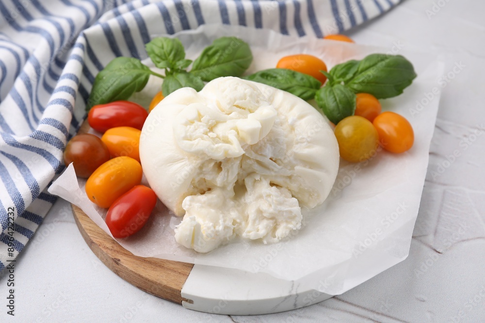 Delicious fresh burrata cheese with basil leaves and tomatoes on white textured table Delicious fresh burrata cheese with basil leaves and tomatoes on white textured table