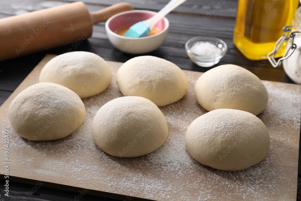 Raw dough balls, yolk, salt and rolling pin on black wooden table Raw dough balls, yolk, salt and rolling pin on black wooden table