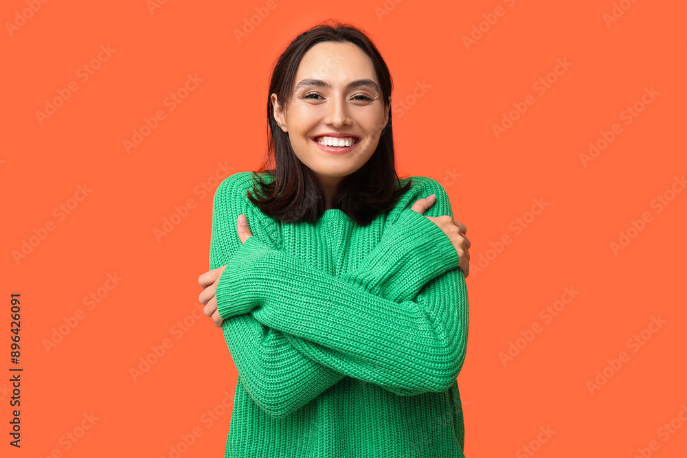 Fototapeta premium Young woman hugging herself on orange background