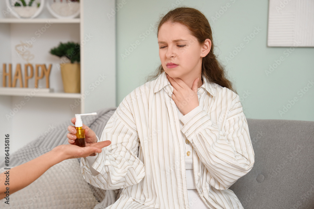 Sick young woman with sore throat taking proposed medical spray at home Sick young woman with sore throat taking proposed medical spray at home