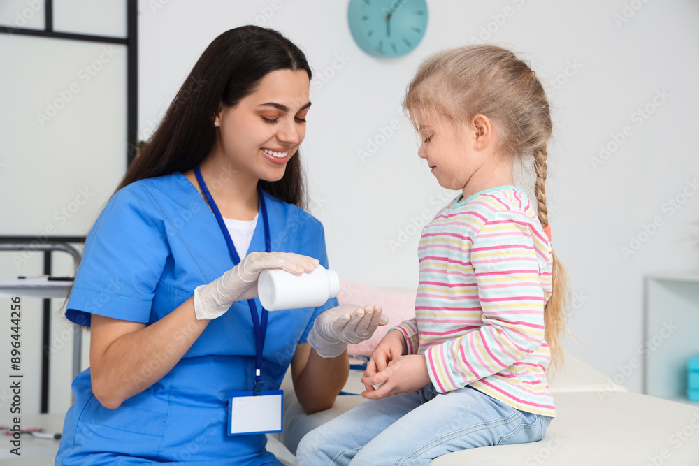 Female pediatrician giving pills to little girl in clinic Female pediatrician giving pills to little girl in clinic