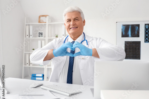 Mature doctor making heart ...