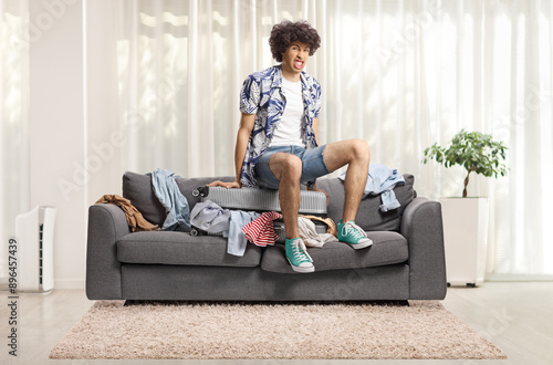 Young man squeezing a suitcase on top of a sofa photo