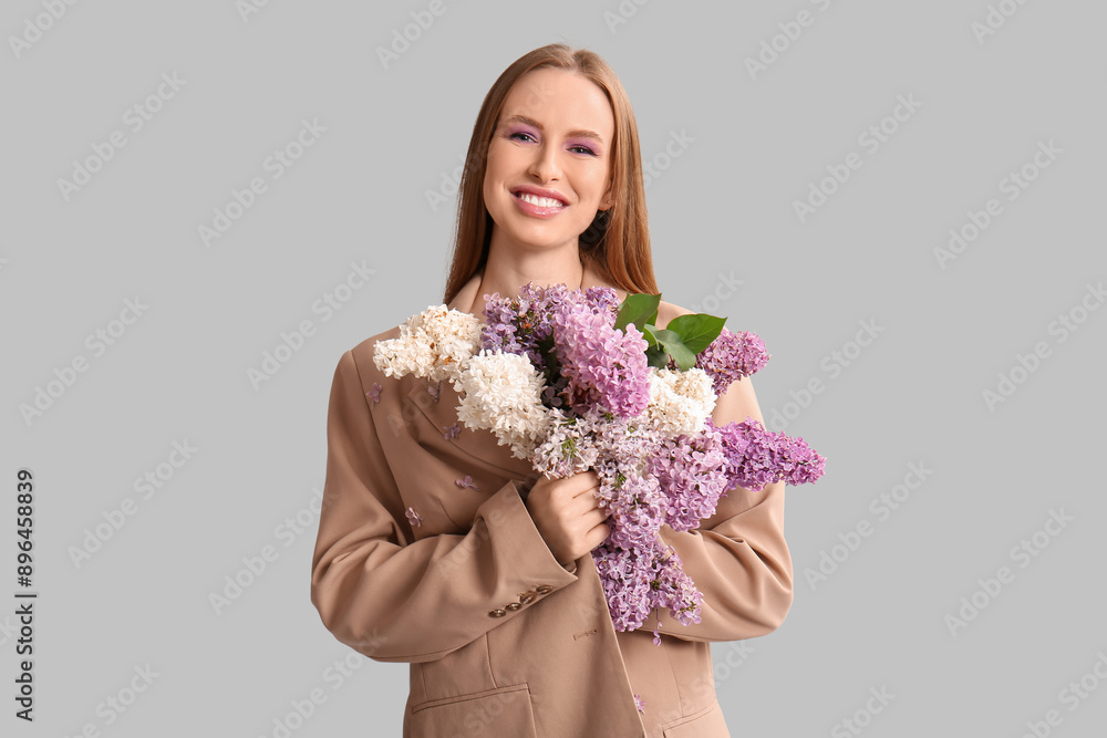 Beautiful young happy woman with bouquet of lilac flowers on grey background Beautiful young happy woman with bouquet of lilac flowers on grey background