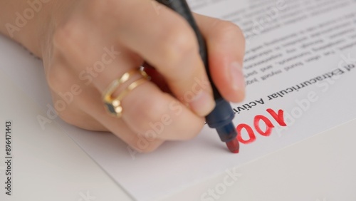 Professional school or college teacher grades a homework exam papers of students. Woman grades test with 100 percent and circles it with red marker.