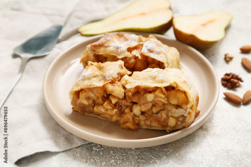 Plate with pieces of tasty pear strudel on grey grunge background Plate with pieces of tasty pear strudel on grey grunge background