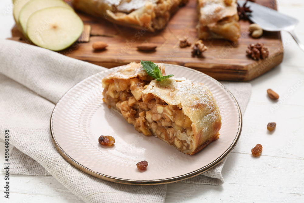 Plate with piece of tasty pear strudel and raisins on white wooden background Plate with piece of tasty pear strudel and raisins on white wooden background