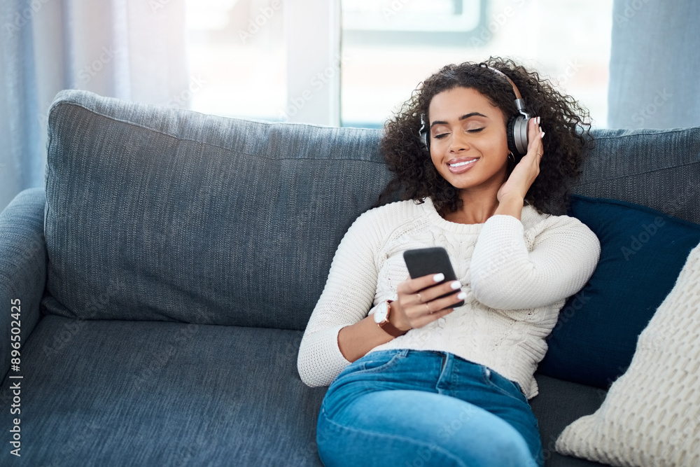 Woman, smile and music with cellphone, headphones and podcast at home or apartment living room. Lady, couch and relax for internet, connectivity and audio streaming for happiness on sofa in lounge Woman, smile and music with cellphone, headphones and podcast at home or apartment living room. Lady, couch and relax for internet, connectivity and audio streaming for happiness on sofa in lounge